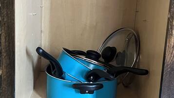 Un pot bleu avec un couvercle et des anses, posé sur une étagère à l’intérieur d’un meuble.