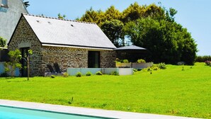 A stone building with a sloped roof, a swimming pool, and a grassy yard. - La Maison de Célestine Bord de mer et Piscine (Plonéour-Lanvern)