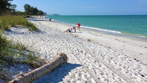Ein Sandstrand mit sonnenbadenden und Spaziergängern.