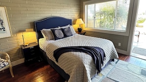 A bedroom with a bed, nightstands, a window with blinds, a brick wall, and a ceiling fan. - Fallbrook’s guest-pool house : An old Hollywood stars escape (Fallbrook)