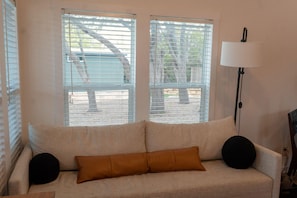 Et værelse med en beige sofa, to sorte runde puder og en gulvlampe.