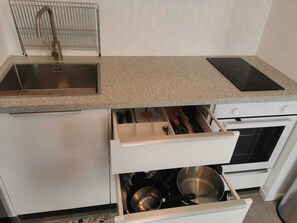 Efficient kitchen with a stainless steel sink, stovetop oven, and microwave.