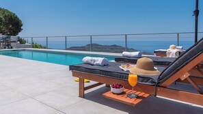 A poolside area with lounge chairs, a table with a bowl of cherries and a glass of orange juice, and towels. - Finca los Paseros Cómpeta by Ruralidays (Málaga)