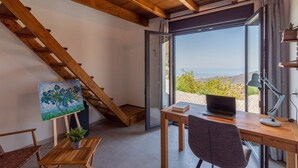 A room with a wooden desk, a laptop, a painting, and a view of the sea. - Finca los Paseros Cómpeta by Ruralidays (Málaga)