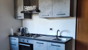 A modern kitchen with grey cabinets, a built-in oven, a sink, and a coffee maker.