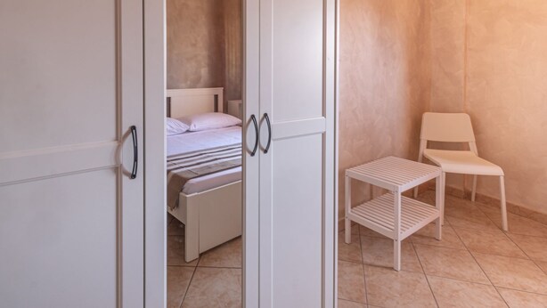 A bedroom with a bed, a chair, and a small table.