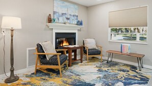 A living room with a fireplace, two armchairs, a coffee table, a floor lamp, and a window with blinds. - King's Bay Point Retreat - Water View (Crystal River)