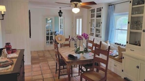 Un comedor con una mesa y sillas de madera, un ventilador de techo y un ventanal con vistas.