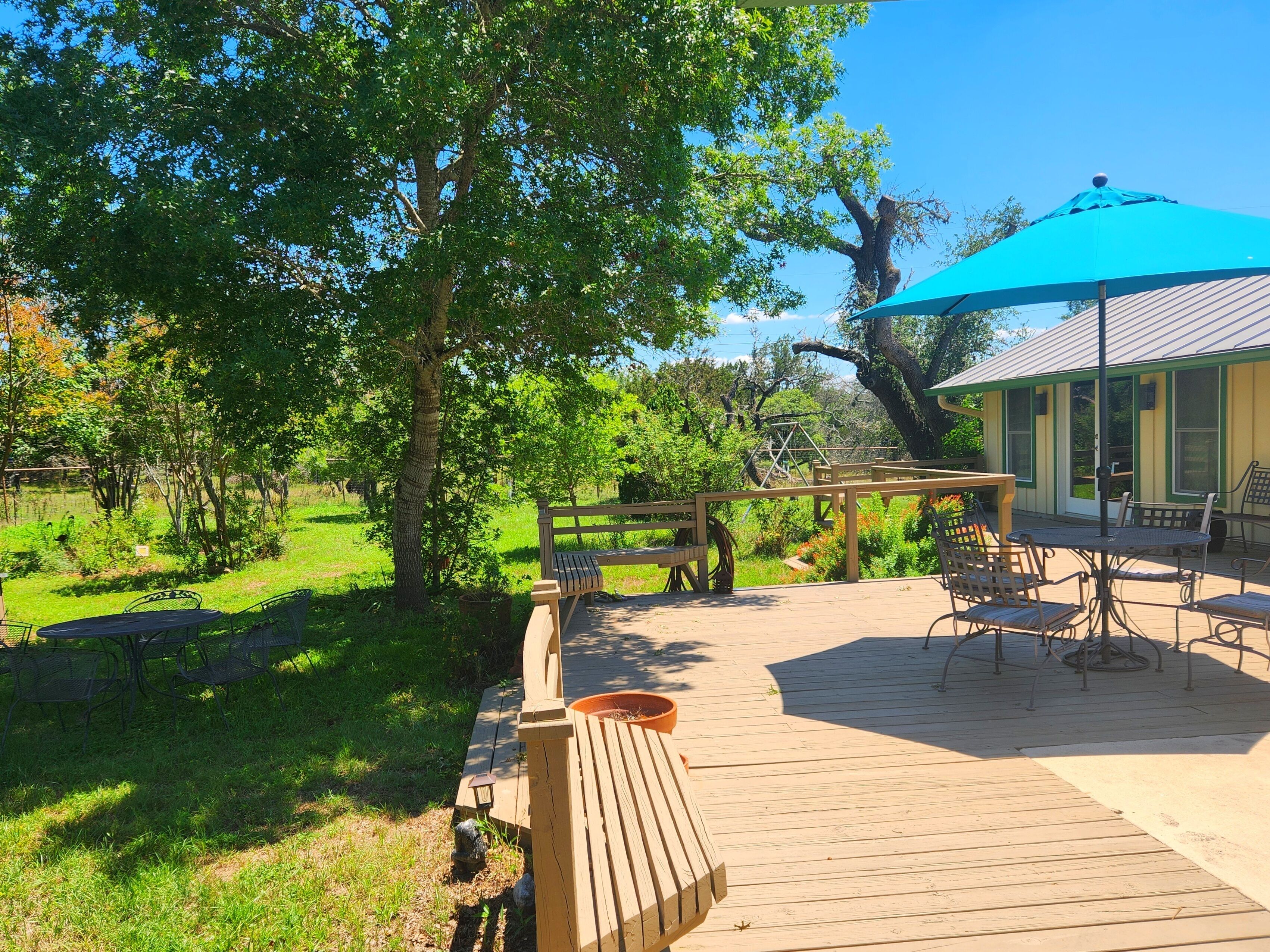 A wooden deck with outdoor furniture, a pergola, and a blue umbrella.