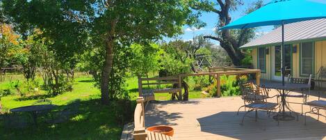 A wooden deck with outdoor furniture, a pergola, and a blue umbrella.