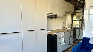 Une cuisine moderne avec des armoires blanches, un réfrigérateur noir et un plan de travail en bois.