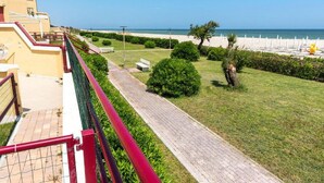 Un sentier menant à une plage, avec une clôture d’un côté et un bâtiment de l’autre.