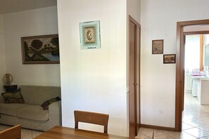 Un salon avec un canapé, une table en bois et une porte donnant sur la cuisine.