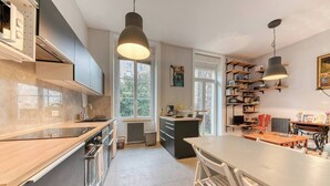 Una cocina moderna con una isla central, iluminación colgante y vistas al exterior.