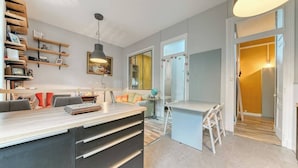 Una cocina moderna con una isla central, estantes empotrados y un comedor con una mesa pequeña y sillas.