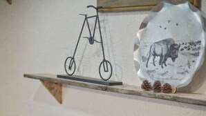 Ein Esstisch mit weißen Tellern, Schüsseln und einer Vase mit weißen Blumen. Über dem Tisch befindet sich ein Regal mit einem Fahrrad und einem dekorativen Teller mit einem Bison.
