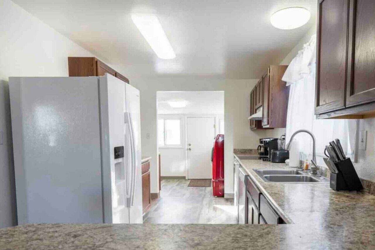 A kitchen with a refrigerator, stove, sink, and cabinets.