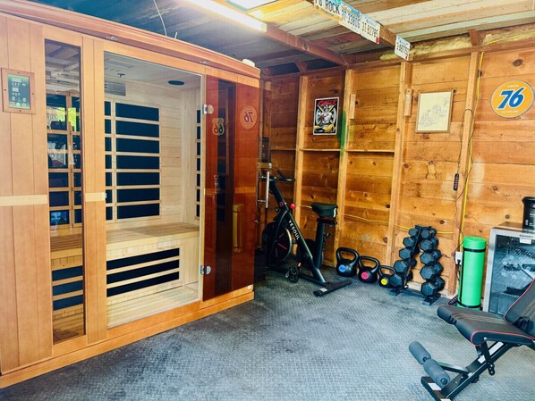 A gym with wooden walls, a treadmill, dumbbells, and a bench.