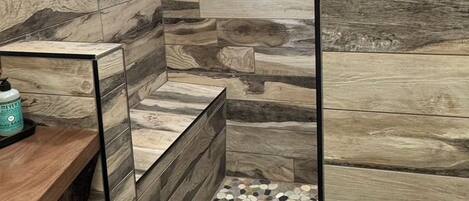 Un baño con diseño de pared de madera, ventana y suelo con estampado de guijarros.