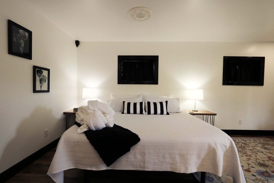 A hotel room with a large bed, two bedside tables, and two wall-mounted lamps.