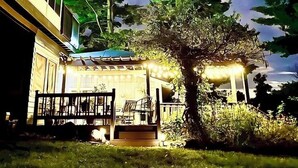 A house with a porch, a tree, and a starry night sky.