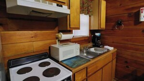 Una cocina compacta con estufa, microondas y lavamanos.