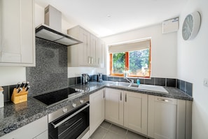 A modern kitchen with granite countertops, stainless steel appliances, and a window with a view of greenery. - The Frome Cottage - A peaceful, rural retreat on the outskirts of Frome, close to Longleat Safari Pa (Beckington)