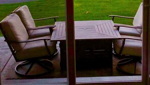 A patio with two chairs and a table, overlooking a grassy area with trees and a road. - C03 Spacious 3BR Townhouse on the Golf Course (Quincy)