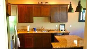 A kitchen with wooden cabinets, a granite countertop, and a 'FAMILY' sign above the cabinets. - C03 Spacious 3BR Townhouse on the Golf Course (Quincy)