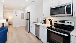 A modern kitchen with white cabinets, stainless steel appliances, and a blue chair.