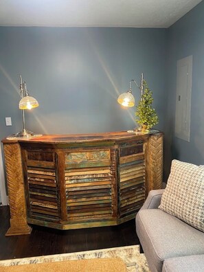 A reception desk with a rustic design, two wall-mounted lamps, and a small potted plant. - The House on Park Avenue (Pineville)