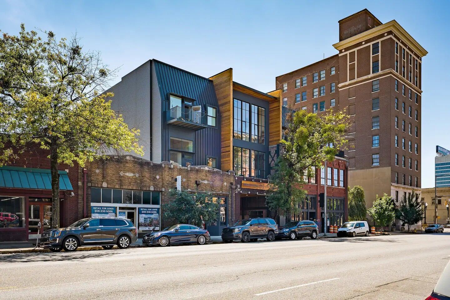 A multi-story building with a mix of modern and traditional architectural styles, featuring large windows and a variety of storefronts on the ground floor.