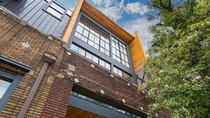 Un immeuble à plusieurs étages, avec des murs en briques apparentes, de grandes fenêtres et une façade en bois.