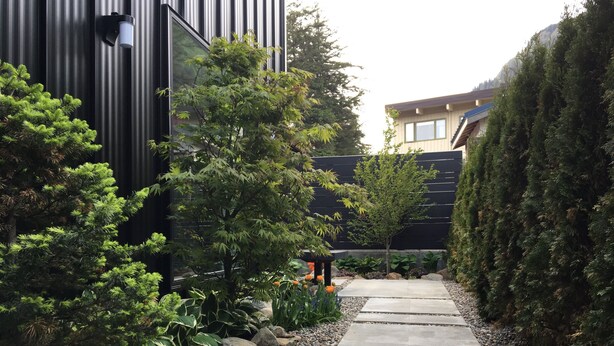 A pathway flanked by various plants and a modern building. - Chalet Suite in Downtown Juneau (Juneau)