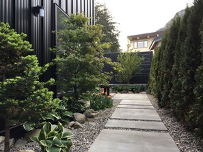 Un camí delimitat per vegetació variada i un edifici modern.