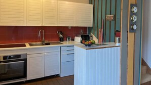 A kitchen with white cabinets, a red backsplash, a built-in oven, a sink, and a fruit bowl on the counter. - House for rent for eight people with garden and beach access (ARZON)