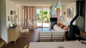 A living room with a sofa, a TV, a fireplace, and a dining area with a table and chairs. - House for rent for eight people with garden and beach access (ARZON)