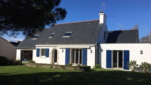 A two-story house with a sloped roof, a stone foundation, and a chimney. - Maison Proche Plage Pour 8 Avec Jardin et Internet (ARZON)