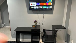 A modern office setup with a desk, chair, and a mounted TV displaying YouTube and other apps. - Sheridan Lodge is a vibrant and safe neighborhood in Washington, DC. (Washington)