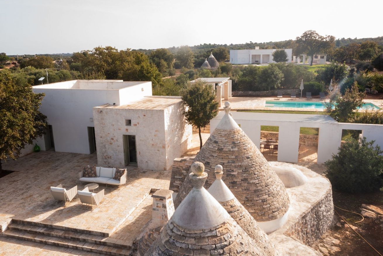 A rooftop terrace with stone structures, outdoor seating, and a swimming pool.
