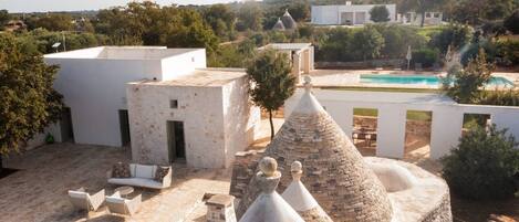 A rooftop terrace with stone structures, outdoor seating, and a swimming pool.