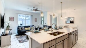 A modern kitchen with a central island, stainless steel appliances, and pendant lighting. - Modern 4BR Home with Private Pool near Disney (Kissimmee)