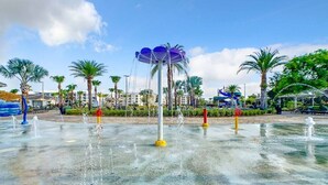 A water fountain area with multiple water jets and a central structure with a blue canopy. - Modern 4BR Home with Private Pool near Disney (Kissimmee)