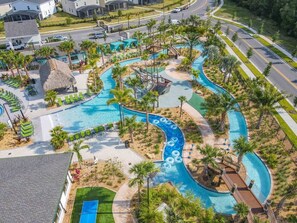 An aerial view of a resort with a winding pool, lounge areas, and palm trees. - Modern Home, Private Pool-September Special Price! (Kissimmee)