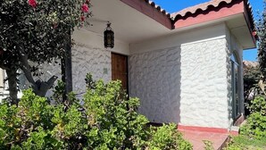 Una casita pequeña de una planta con techo de tejas rojas y paredes blancas.