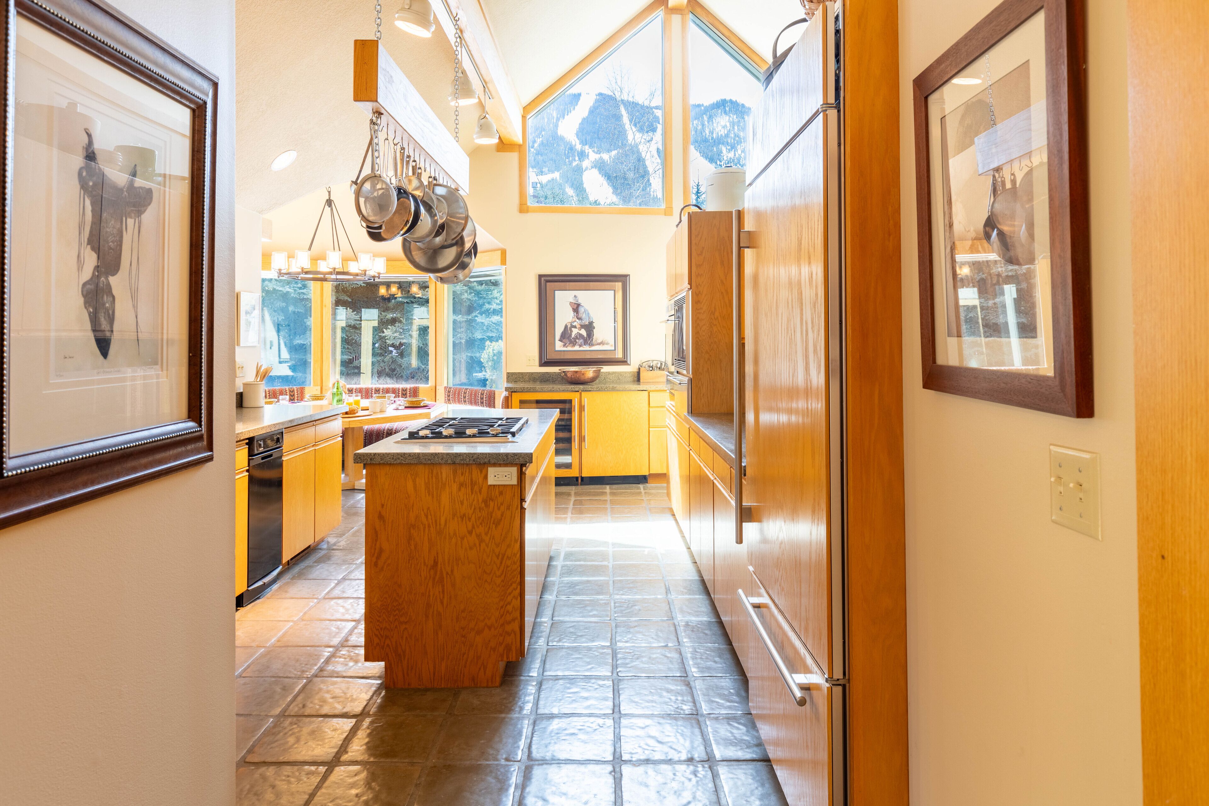 A kitchen with wooden cabinets, a central island, and hanging pots.