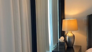 Een hotelkamer met een grote spiegel, een bedlampje, een klein tafeltje met zakdoekjes en een bed.