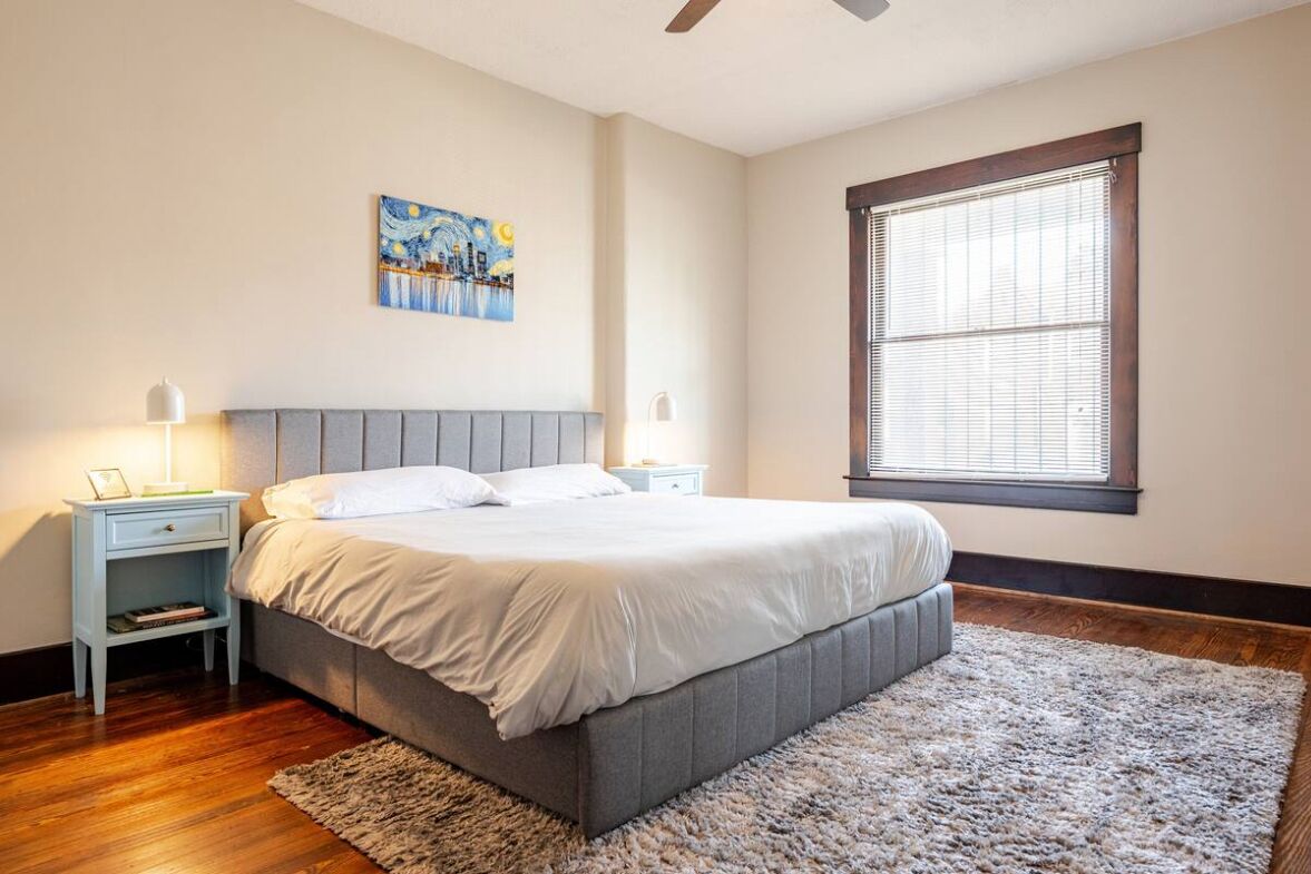 Una camera da letto con un letto, comodini, un quadro e una finestra.