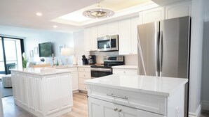 Une cuisine moderne avec des meubles blancs, des appareils en acier inoxydable et un îlot central.