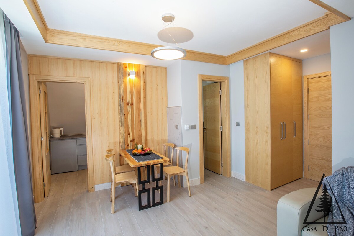 Une cuisine moderne avec des meubles en bois, une table à manger avec des chaises et un four encastré.
